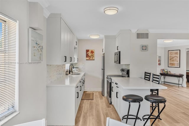 5800 NE 22nd Way Unit 523, Fort Lauderdale, FL 33308 - kitchen featuring appliances with stainless steel finishes, a kitchen bar, a peninsula, light countertops, and crown molding