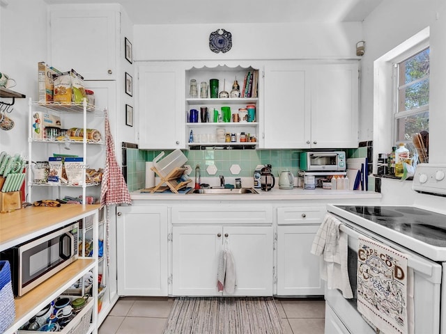 3210 E Elizabeth St, Miami, FL 33133 - kitchen with white electric range oven, light tile patterned floors, stainless steel microwave, and white cabinets