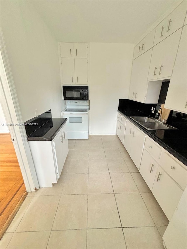 539 NE 82nd Ter, Miami, FL 33138 - kitchen with white electric stove, black microwave, light tile patterned floors, white cabinets, and dark countertops