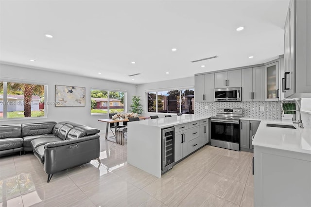 8115 NW 185th Ter, Hialeah, FL 33015 - kitchen featuring appliances with stainless steel finishes, beverage cooler, gray cabinetry, open floor plan, and light countertops