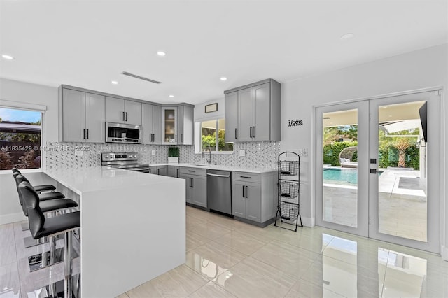 8115 NW 185th Ter, Hialeah, FL 33015 - kitchen with gray cabinetry, stainless steel appliances, a peninsula, backsplash, and recessed lighting