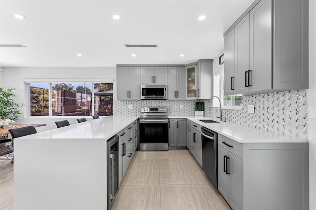 8115 NW 185th Ter, Hialeah, FL 33015 - kitchen with appliances with stainless steel finishes, gray cabinetry, a peninsula, healthy amount of natural light, and recessed lighting