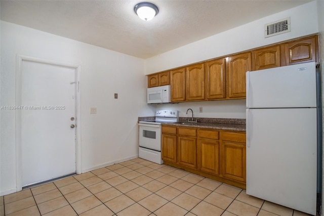 9443 SW 174th St Unit 9443, Palmetto Bay, FL 33157 - kitchen featuring white appliances, brown cabinets, dark countertops, and light tile patterned floors