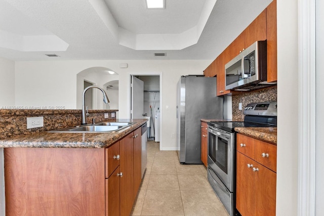 3066 S Red Mangrove Ln S Unit 201-2, Dania Beach, FL 33312 - kitchen featuring appliances with stainless steel finishes, a raised ceiling, brown cabinets, and backsplash