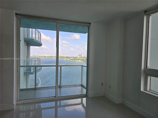 1900 N Bayshore Dr Unit 1803, Miami, FL 33132 - unfurnished room with floor to ceiling windows, a water view, a textured ceiling, and tile patterned flooring