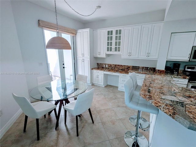 1900 Oceanwalk Ln Unit 123, Lauderdale By The Sea, FL 33062 - kitchen featuring stainless steel range oven, built in desk, white cabinets, dark stone countertops, and glass insert cabinets