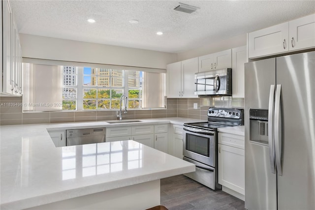 37 Majorca Ave Unit 401, Coral Gables, FL 33134 - kitchen with stainless steel appliances, a textured ceiling, dark wood-type flooring, backsplash, and white cabinets