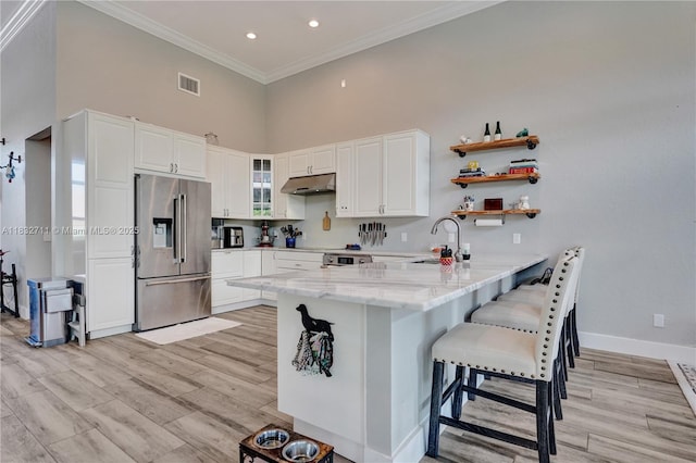17809 Southwick Way, Boca Raton, FL 33498 - kitchen featuring stainless steel refrigerator with ice dispenser, a peninsula, a high ceiling, under cabinet range hood, and light stone counters