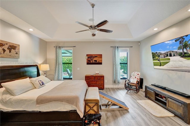 17809 Southwick Way, Boca Raton, FL 33498 - bedroom featuring a tray ceiling, multiple windows, recessed lighting, light wood-style floors, and a ceiling fan