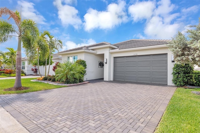 15734 SW Egret Coast Dr, Port St Lucie, FL 34987 - view of front of property featuring a garage, decorative driveway, stucco siding, a tile roof, and a front yard
