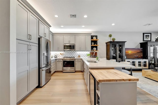 15734 SW Egret Coast Dr, Port St Lucie, FL 34987 - kitchen with appliances with stainless steel finishes, open shelves, a peninsula, butcher block countertops, and light wood-style floors