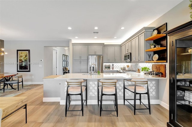 15734 SW Egret Coast Dr, Port St Lucie, FL 34987 - kitchen featuring gray cabinetry, open shelves, a kitchen breakfast bar, appliances with stainless steel finishes, and recessed lighting
