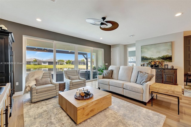 15734 SW Egret Coast Dr, Port St Lucie, FL 34987 - living room with light wood-style floors, recessed lighting, a ceiling fan, and a water view