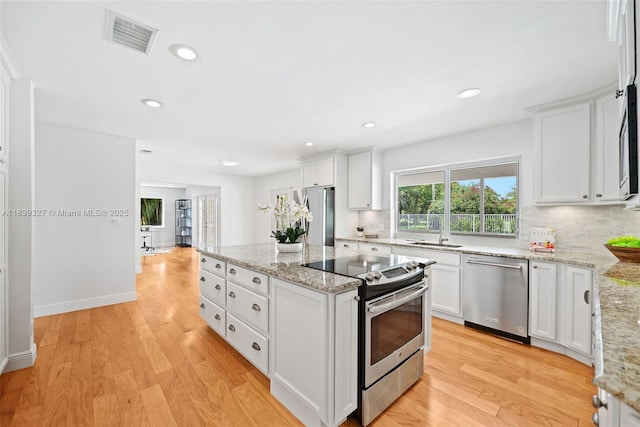7545 Banyan Way, Tamarac, FL 33321 - kitchen featuring appliances with stainless steel finishes, tasteful backsplash, a kitchen island, white cabinetry, and recessed lighting