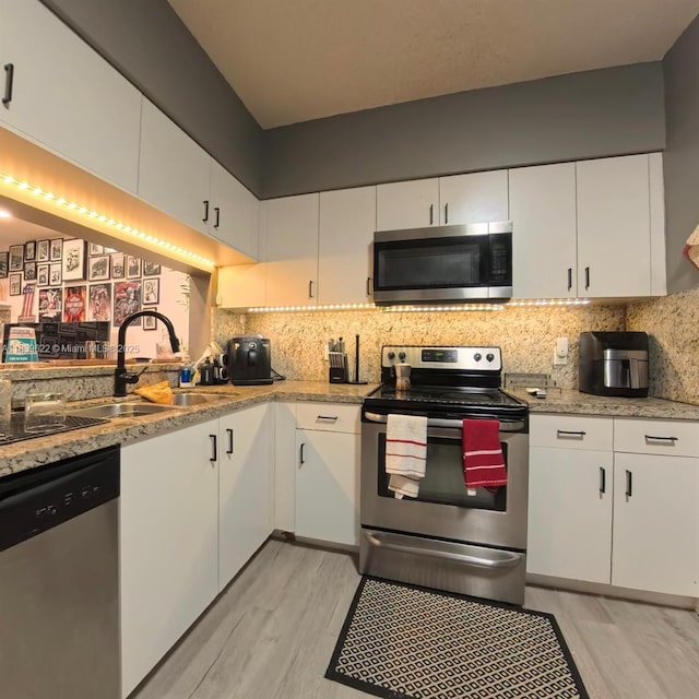 16652 Hemingway Dr, Weston, FL 33326 - kitchen featuring appliances with stainless steel finishes, light wood-style floors, white cabinets, and decorative backsplash