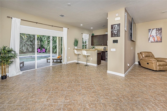10608 NW 36th St, Coral Springs, FL 33065 - kitchen featuring open floor plan, a breakfast bar, light countertops, dark brown cabinets, and a textured ceiling