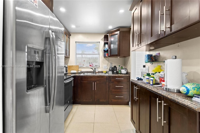 6600 Royal Palm Blvd Unit 103B, Margate, FL 33063 - kitchen featuring appliances with stainless steel finishes, dark brown cabinetry, light tile patterned floors, dark stone countertops, and glass insert cabinets