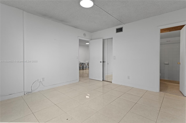 6600 Royal Palm Blvd Unit 103B, Margate, FL 33063 - unfurnished bedroom featuring light tile patterned flooring, a textured ceiling, ensuite bathroom, and a closet