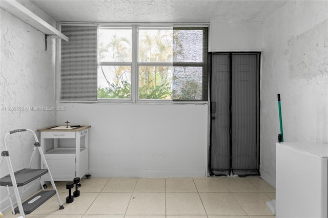 6600 Royal Palm Blvd Unit 103B, Margate, FL 33063 - laundry room featuring plenty of natural light, a textured ceiling, tile patterned flooring, and a textured wall