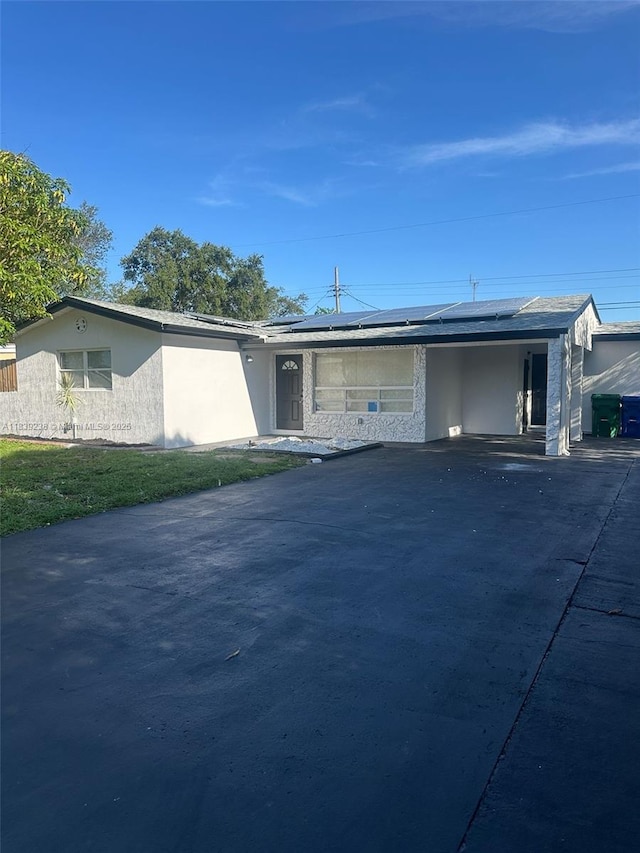 6990 SW 28th St, Miramar, FL 33023 - view of front of house with roof mounted solar panels, stucco siding, driveway, and a carport