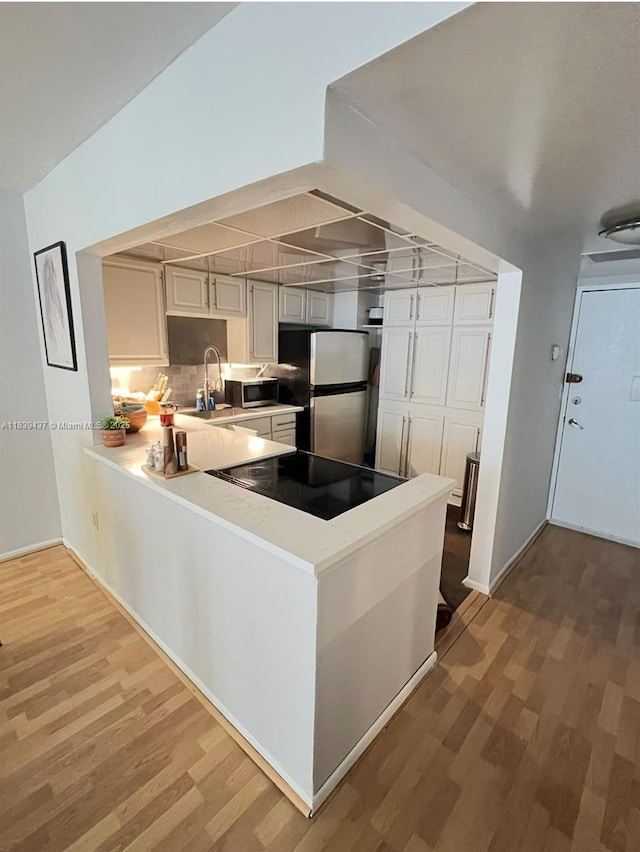 1228 W Ave Unit 911, Miami Beach, FL 33139 - kitchen with stainless steel appliances, light wood finished floors, light countertops, and a peninsula