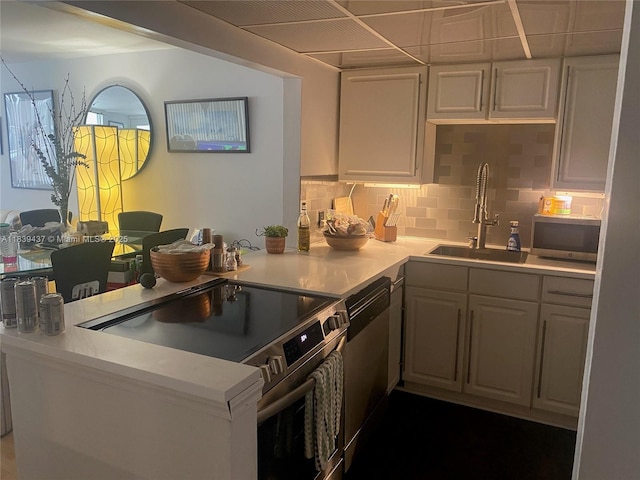 1228 W Ave Unit 911, Miami Beach, FL 33139 - kitchen with appliances with stainless steel finishes, a peninsula, tasteful backsplash, light countertops, and white cabinets