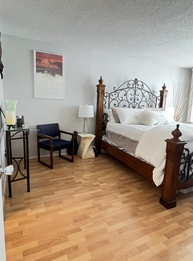 1228 W Ave Unit 911, Miami Beach, FL 33139 - bedroom with light wood-style flooring and a textured ceiling