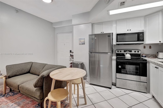 3051 SW 27th Ave Unit 402, Miami, FL 33133 - kitchen with stainless steel appliances, white cabinetry, and light tile patterned floors