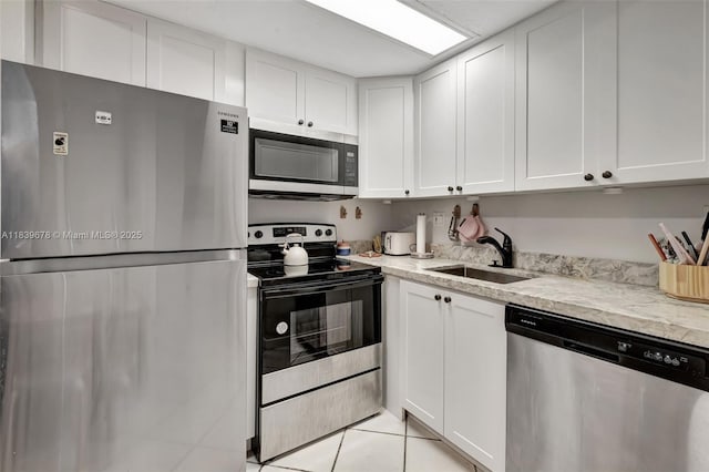 3051 SW 27th Ave Unit 402, Miami, FL 33133 - kitchen with appliances with stainless steel finishes, white cabinets, light tile patterned flooring, and light stone countertops