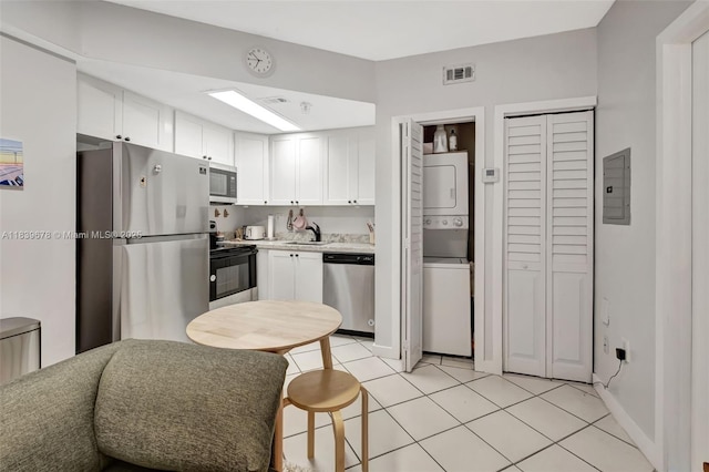 3051 SW 27th Ave Unit 402, Miami, FL 33133 - kitchen with stainless steel appliances, stacked washing machine and dryer, white cabinetry, electric panel, and light countertops