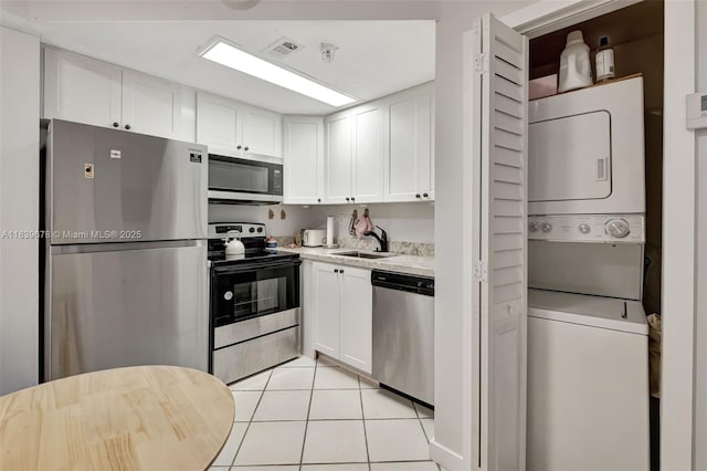 3051 SW 27th Ave Unit 402, Miami, FL 33133 - kitchen featuring stainless steel appliances, stacked washer / dryer, light countertops, white cabinets, and light tile patterned floors