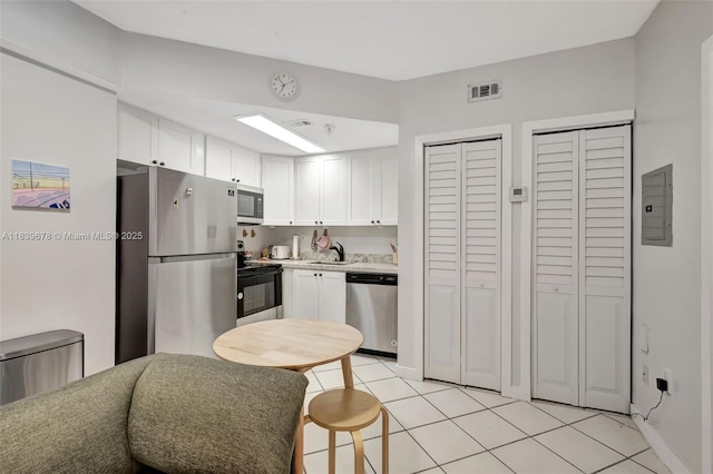 3051 SW 27th Ave Unit 402, Miami, FL 33133 - kitchen with appliances with stainless steel finishes, electric panel, light countertops, white cabinetry, and light tile patterned flooring