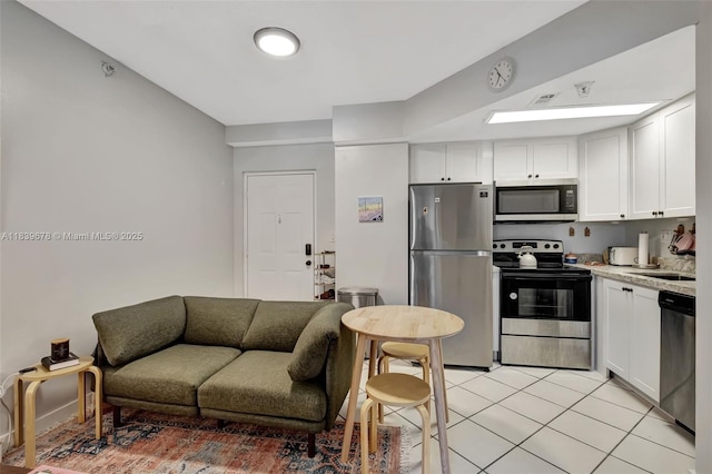 3051 SW 27th Ave Unit 402, Miami, FL 33133 - kitchen with appliances with stainless steel finishes, light tile patterned floors, white cabinets, and light countertops