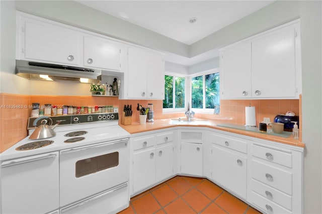 2665 SW 17th Ave, Miami, FL 33133 - kitchen with under cabinet range hood, electric stove, white cabinets, light tile patterned flooring, and tile counters