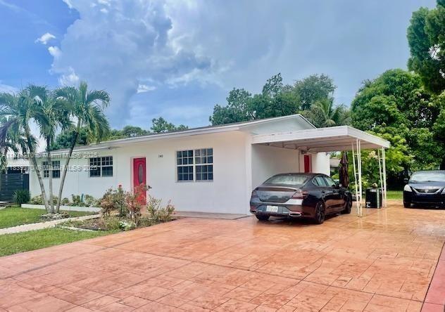 140 NW 199th St, Miami Gardens, FL 33169 - view of front of house with decorative driveway, an attached carport, and stucco siding