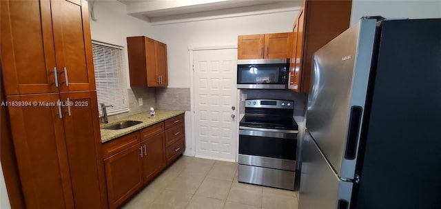 1887 NW 66th St, Miami, FL 33147 - kitchen with stainless steel appliances, light tile patterned flooring, light stone counters, and brown cabinetry