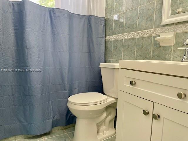 330 W 40th Pl, Hialeah, FL 33012 - bathroom with tile patterned flooring, tile walls, vanity, and curtained shower