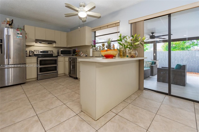 906 Cardinal Pl, Homestead, FL 33035 - kitchen featuring stainless steel appliances, ceiling fan, cream cabinetry, under cabinet range hood, and a peninsula