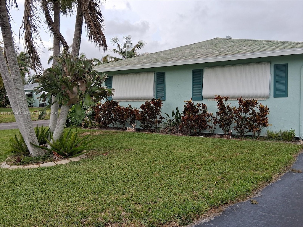 635 Hummingbird Ln, Delray Beach, FL 33445 - view of front of home featuring a front yard, stucco siding, and a shingled roof