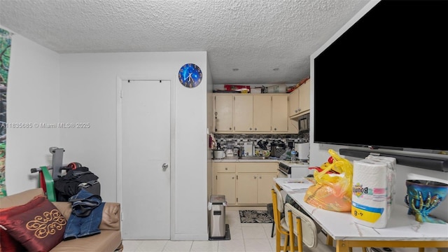 521 SE 5th St, Hialeah, FL 33010 - kitchen featuring cream cabinets, light countertops, a textured ceiling, light tile patterned flooring, and tasteful backsplash