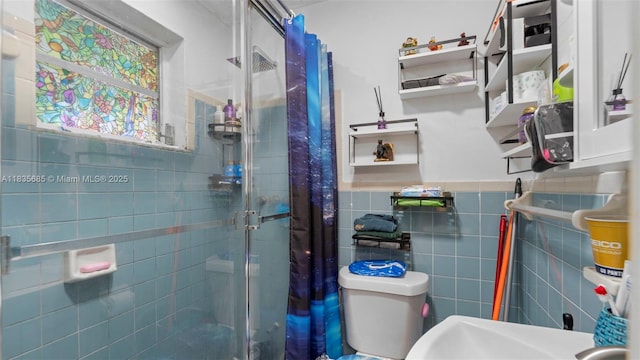 521 SE 5th St, Hialeah, FL 33010 - bathroom featuring a stall shower, tile walls, and a wainscoted wall