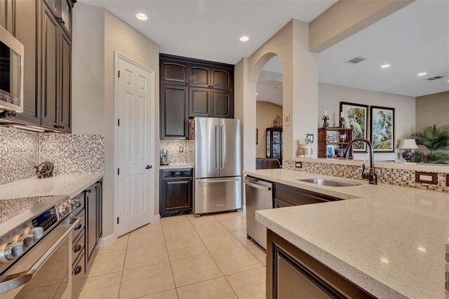 19252 N Hibiscus St, Weston, FL 33332 - kitchen featuring stainless steel appliances, decorative backsplash, arched walkways, light tile patterned floors, and recessed lighting