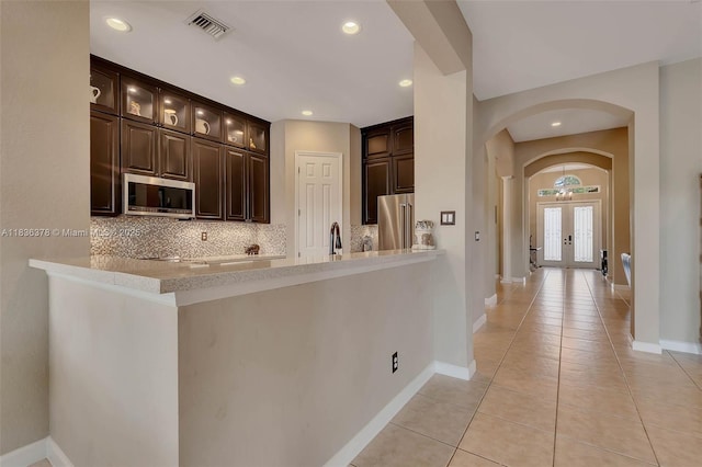 19252 N Hibiscus St, Weston, FL 33332 - kitchen with arched walkways, decorative backsplash, dark brown cabinets, light countertops, and recessed lighting
