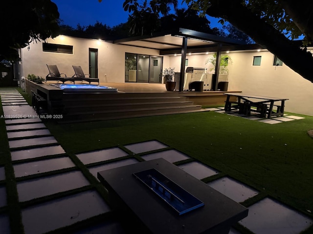 641 Nightingale Ave, Miami Springs, FL 33166 - back of house at night featuring stucco siding, an outdoor kitchen, and an outdoor hot tub