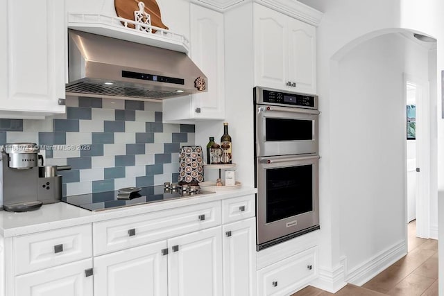 9031 SW 66th Ter, Miami, FL 33173 - kitchen with double oven, black electric stovetop, ventilation hood, backsplash, and white cabinets