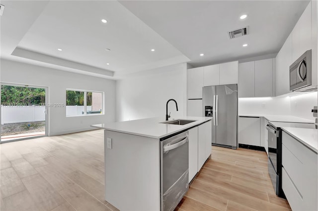 1563 NW 94th Way Unit 09, Coral Springs, FL 33071 - kitchen featuring appliances with stainless steel finishes, modern cabinets, a tray ceiling, light countertops, and an island with sink