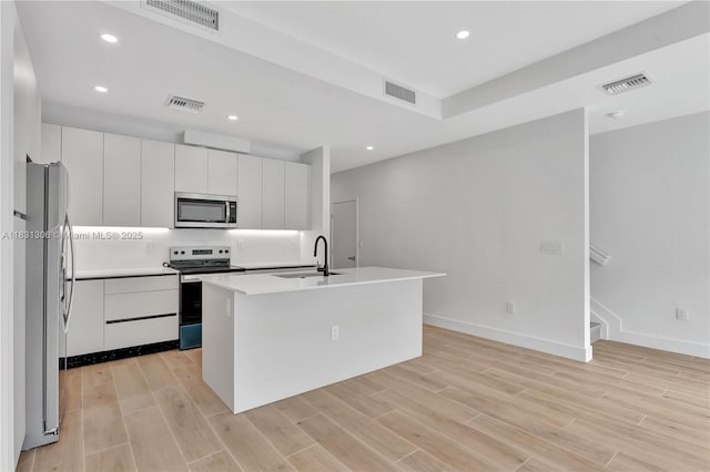 1563 NW 94th Way Unit 09, Coral Springs, FL 33071 - kitchen with stainless steel appliances, light wood-type flooring, recessed lighting, white cabinets, and a center island with sink