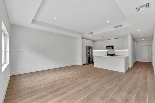 1563 NW 94th Way Unit 09, Coral Springs, FL 33071 - unfurnished living room with a tray ceiling, light wood finished floors, and recessed lighting