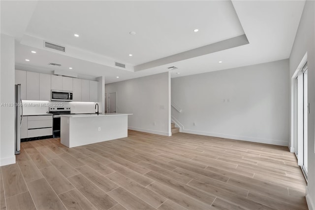 1563 NW 94th Way Unit 09, Coral Springs, FL 33071 - unfurnished living room with a tray ceiling, stairway, recessed lighting, and light wood-style flooring