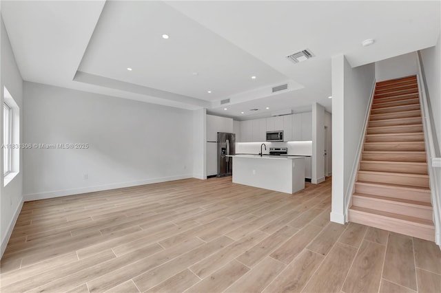 1563 NW 94th Way Unit 09, Coral Springs, FL 33071 - unfurnished living room with a tray ceiling, stairs, light wood-type flooring, and recessed lighting